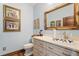 Powder room featuring marble countertop, sink with painted floral motif, framed mirror, and decorative wall art at 3005 S Miller Rd, Valrico, FL 33596