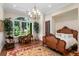 Bedroom with large window, chandelier, desk, and wood frame bed with linens at 3005 S Miller Rd, Valrico, FL 33596