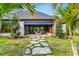 Rear exterior with stone pathway leading to patio, blue awning, lush landscaping, and palm trees at 3005 S Miller Rd, Valrico, FL 33596