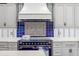 Close-up of a stylish kitchen with blue oven range, tiled backsplash, and custom white cabinets at 3005 S Miller Rd, Valrico, FL 33596
