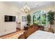 This stunning main bedroom includes a chandelier, desk, an adjacent bathroom, and large windows to view the outdoors at 3005 S Miller Rd, Valrico, FL 33596