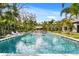 Backyard pool with shimmering water, surrounded by a stone deck, lush landscaping, and pool furniture at 3005 S Miller Rd, Valrico, FL 33596