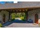 Elegant stone porte cochere featuring wood beams, arched doorways and a landscaped view to the main house at 3005 S Miller Rd, Valrico, FL 33596