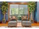 Cozy sitting area with two chairs, ottomans, decorative pillows, and green plants by the window at 3005 S Miller Rd, Valrico, FL 33596