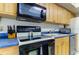 A view of the kitchen with wooden cabinets, black oven, dark blue countertops and stainless steel dishwasher at 5396 Gulf Blvd # 110, St Pete Beach, FL 33706