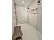 Modern walk-in shower with marble-like tiles, a built-in niche, and a comfortable wooden bench at 7425 245Th E St, Myakka City, FL 34251