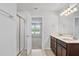 Bathroom featuring a double vanity, quartz counters, glass shower and white walls at 10822 Windswept Garden Way, Tampa, FL 33647