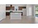 Kitchen with island features stainless steel appliances, dark brown cabinets, and tile floors at 10822 Windswept Garden Way, Tampa, FL 33647