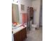 Bright bathroom with wooden cabinet, decorated mirror, and neutral tile floors at 10933 Subtle Trail Dr, Riverview, FL 33569