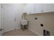 Bright laundry room featuring white cabinets, tile flooring, sink and door access to the rest of the home at 16206 Diamond Bay Dr, Wimauma, FL 33598