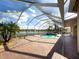 A screened-in pool area with brick pavers, tropical landscaping and scenic views of the lake beyond at 16206 Diamond Bay Dr, Wimauma, FL 33598