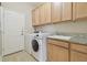 Functional laundry room with front-load washer, dryer, granite countertops, sink and wood cabinets at 19317 Hawk Valley Dr, Tampa, FL 33647