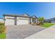 Beautiful one-story home with a three-car garage, brick-paved driveway, and a well-maintained lawn at 33277 Rosewood Bark Way, Wesley Chapel, FL 33545