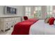 Primary bedroom featuring a dresser, mounted TV, and a king bed adorned with a red quilt at 11563 Callisia Dr, Odessa, FL 33556