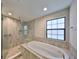 Serene bathroom with a soaking tub, glass enclosed shower, and a large window for natural light at 12779 Fisherville Way, Riverview, FL 33579