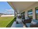 Relaxing covered patio with stylish outdoor seating and dining, overlooking a green lawn and fenced backyard at 12779 Fisherville Way, Riverview, FL 33579