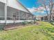 Landscaped backyard featuring a screened patio and a well-maintained lawn with vibrant tropical plants and mulch beds at 13252 Norman Cir, Hudson, FL 34669