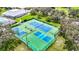 Aerial view of pristine community tennis and pickleball courts surrounded by lush greenery and trees at 13252 Norman Cir, Hudson, FL 34669