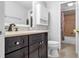 Bathroom featuring dark wood cabinets, neutral countertops, framed mirror, and tile shower at 15701 Springmoss Ln, Tampa, FL 33624
