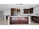 Modern kitchen featuring dark wood cabinets, stainless steel appliances, and a sleek white countertop island at 15701 Springmoss Ln, Tampa, FL 33624