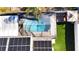 Aerial view of a private screened-in pool with clear blue water, and solar panels adjacent at 15701 Springmoss Ln, Tampa, FL 33624