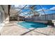 Inviting screened-in pool area featuring a sparkling pool, brick patio, and waterfall feature at 15701 Springmoss Ln, Tampa, FL 33624