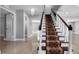 Elegant staircase with dark wood railing, carpet runner, and a modern chandelier at 15701 Springmoss Ln, Tampa, FL 33624