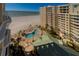 Aerial view of a beachfront condominium featuring a pool, palm trees, and beach access at 10 Papaya St # 1404, Clearwater Beach, FL 33767