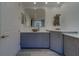 Modern bathroom featuring blue cabinets, a large mirror, and tiled floors plus an adjacent doorway at 10 Papaya St # 1404, Clearwater Beach, FL 33767