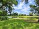 Serene backyard view overlooking a pond and golf course framed by mature trees and lush greenery at 16311 Colwood Dr, Odessa, FL 33556