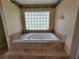 Relaxing bathtub area features a tile surround and a window for natural light at 16311 Colwood Dr, Odessa, FL 33556