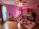 Fun bedroom featuring a lofted bed with built in slide, wood floors, and bright pink walls at 16311 Colwood Dr, Odessa, FL 33556