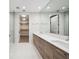A modern bathroom has double sinks with wood cabinets and a walk-in glass shower, complemented by ample lighting and closet space at 301 1St S St # 1605, St Petersburg, FL 33701