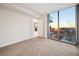 A bedroom features a large window with views of the cityscape and a sunset sky, plus neutral carpet and minimalist decor at 301 1St S St # 1605, St Petersburg, FL 33701