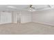 Large, carpeted bedroom with neutral walls, tray ceiling, ceiling fan, and double door entry at 32346 Sapna Chime Dr, Wesley Chapel, FL 33545