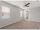 Minimalist bedroom featuring neutral carpet, ceiling fan and a peek into the bathroom at 32346 Sapna Chime Dr, Wesley Chapel, FL 33545