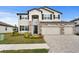 Two-story home with a manicured lawn, brick accents, and a three car garage at 32346 Sapna Chime Dr, Wesley Chapel, FL 33545