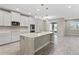 Bright kitchen boasts white cabinets, quartz countertops, stainless appliances, and an island, open to the living area at 32346 Sapna Chime Dr, Wesley Chapel, FL 33545