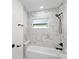 Close-up of a bath with marble tiles, matte black fixtures and shower head at 3401 E Hanna Ave, Tampa, FL 33610