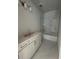 Bathroom featuring white cabinets, marble flooring, and a shower-over-tub with glass door at 509 N Bradford Ave, Tampa, FL 33609