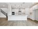 Modern, open-concept kitchen featuring white cabinets, a large island, stainless steel appliances, and wood flooring at 509 N Bradford Ave, Tampa, FL 33609