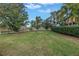 A backyard lawn is surrounded by shrubbery and small trees and overlooks a pond in the distance at 650 Saxony Blvd, St Petersburg, FL 33716