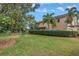 A well-manicured backyard and lawn lead up to a two story home with tan siding and a lush green lawn at 650 Saxony Blvd, St Petersburg, FL 33716
