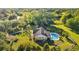 Aerial view of home highlighting a pool, green lawn, and patio area, framed by mature trees and fencing at 7213 Jones Rd, Odessa, FL 33556