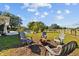 Spacious backyard features a fire pit with Adirondack chairs, lush lawn and a pool in the distance at 7213 Jones Rd, Odessa, FL 33556