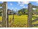 Inviting backyard view with a pool, lush lawn, and a charming wooden fence, seen through a rustic gate at 7213 Jones Rd, Odessa, FL 33556