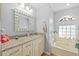 Bright bathroom featuring a granite countertop, decorative mirror, and a large soaking tub at 7213 Jones Rd, Odessa, FL 33556