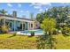 Lush backyard features an in-ground pool, covered patio with outdoor seating, and landscaping at 7213 Jones Rd, Odessa, FL 33556