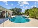 View of the in-ground pool surrounded by lush landscaping and a spacious patio with outdoor seating at 7213 Jones Rd, Odessa, FL 33556