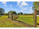 Wide open field showcases the property's spaciousness and potential, framed by wooden fencing at 7213 Jones Rd, Odessa, FL 33556